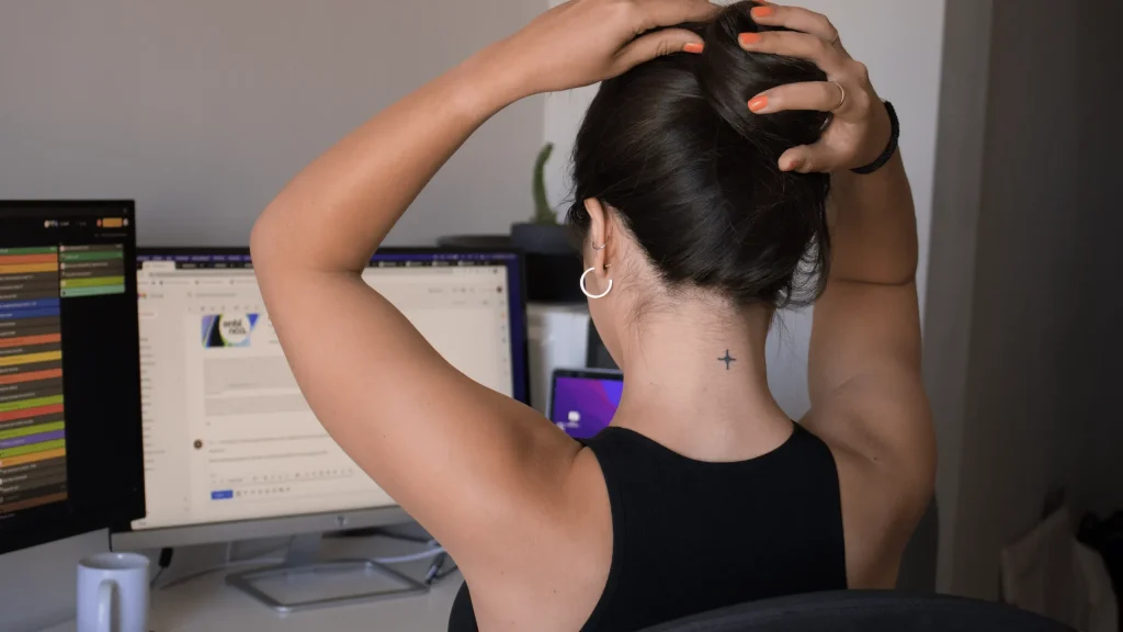Femme de dos devant un écran, les mains sur la nuque