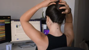 Femme de dos devant un écran, les mains sur la nuque