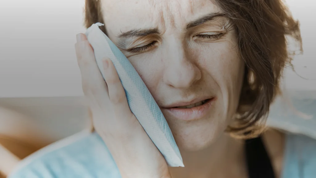 Femme tenant une compresse contre la mâchoire