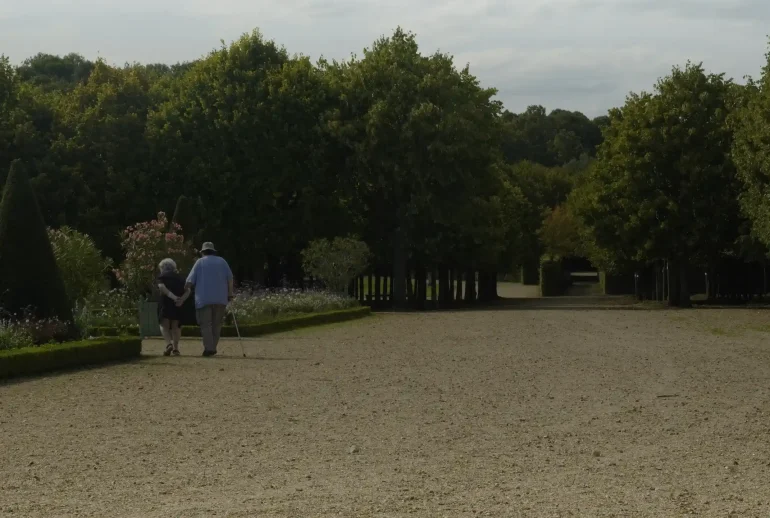 Un couple de marcheurs âgés dans une allée de parc
