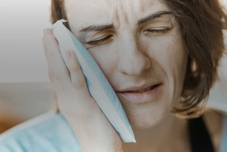 Femme tenant une compresse contre la mâchoire